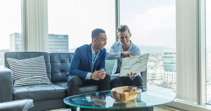 two men in suit sitting on sofa